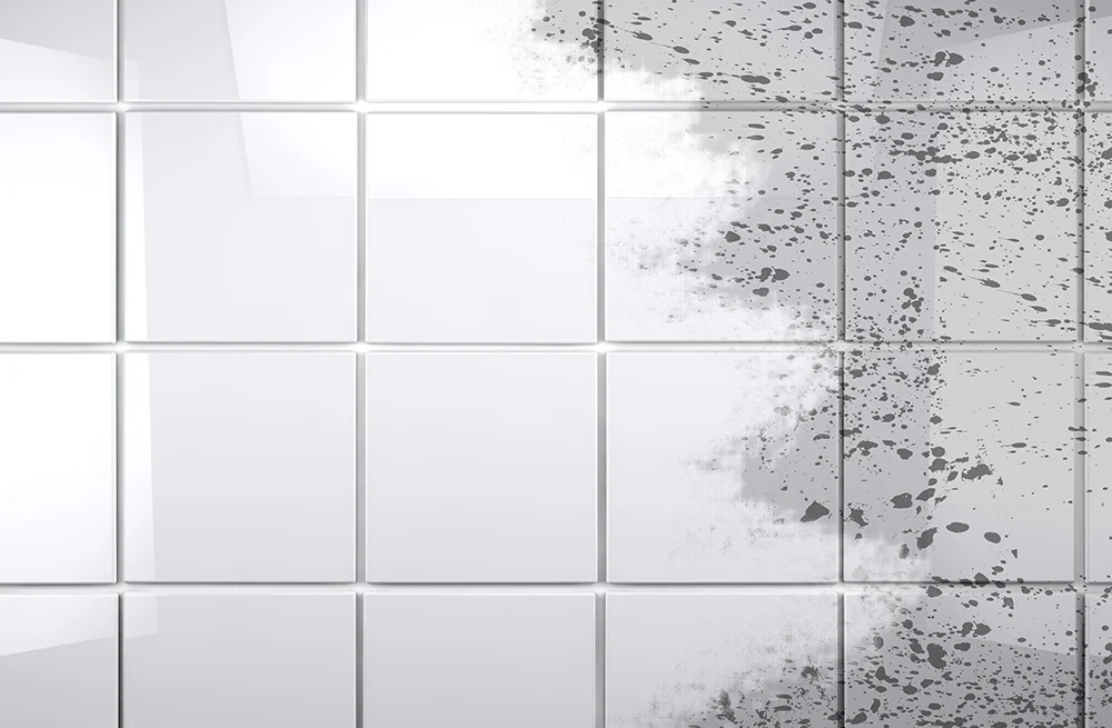 White tile with a cleaned area beside dark buildup on the tile and grout.